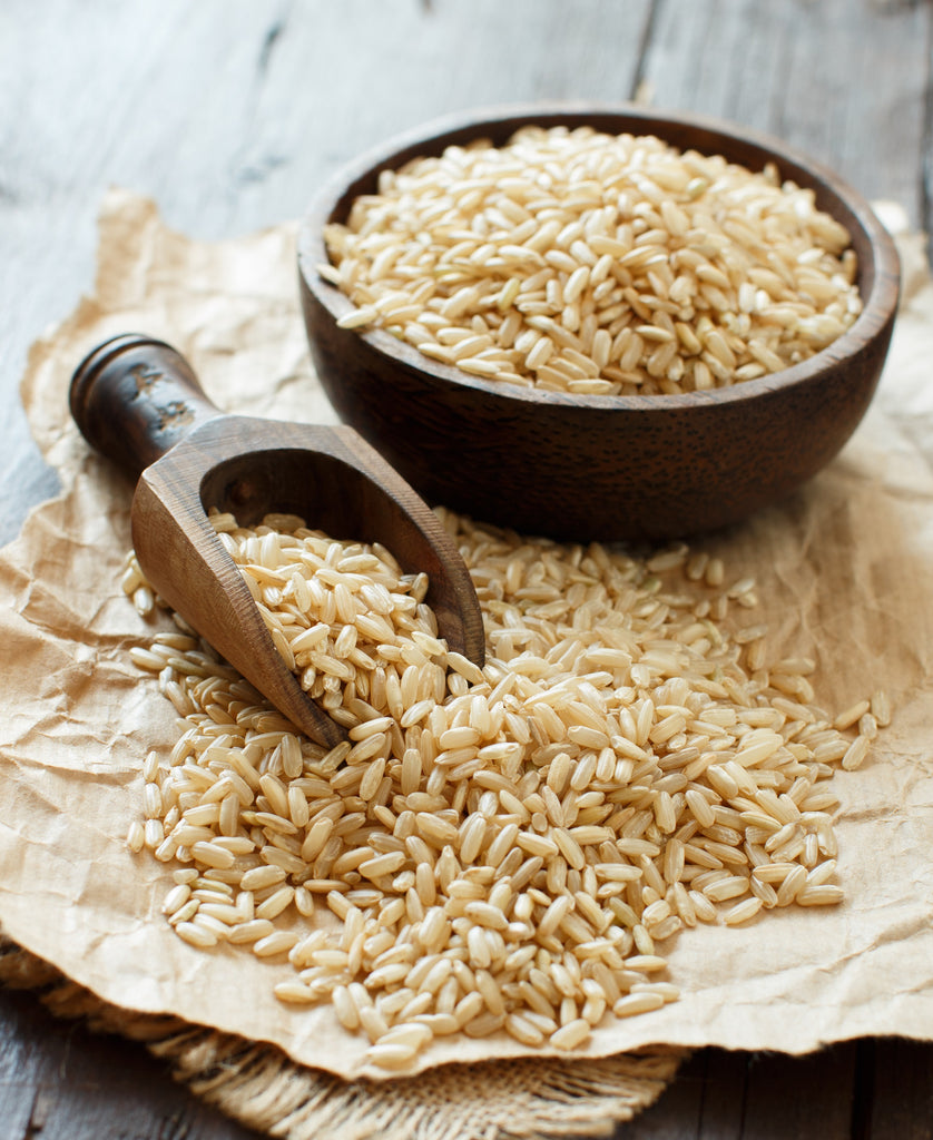 brown rice in a bowl with a wooden spoon